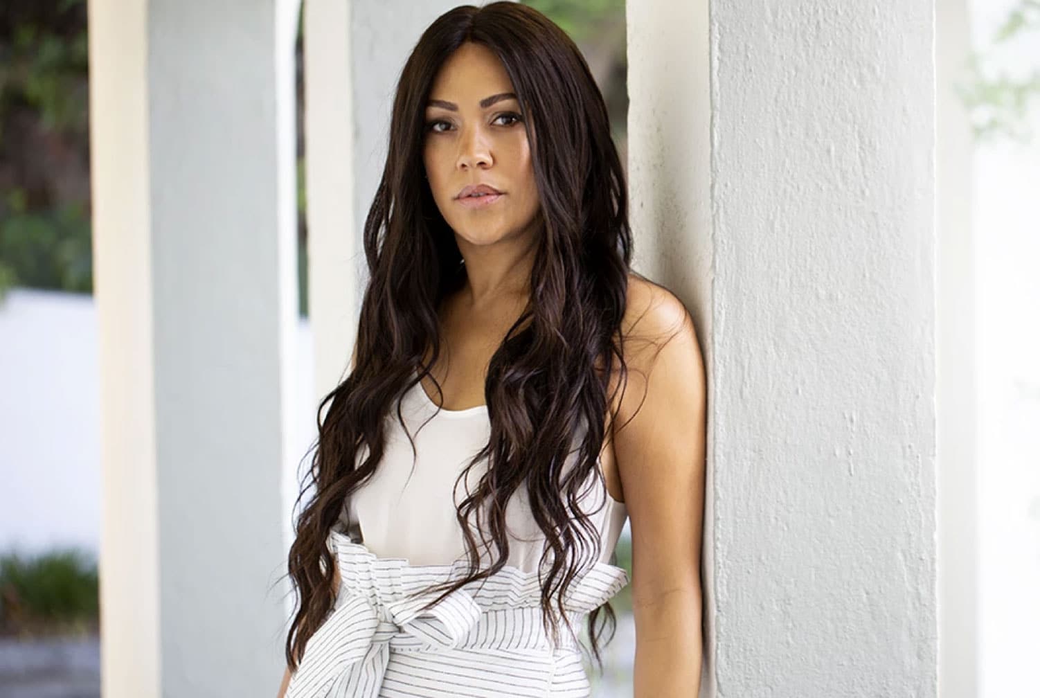 Portrait of Shani Darden leaning against a white column