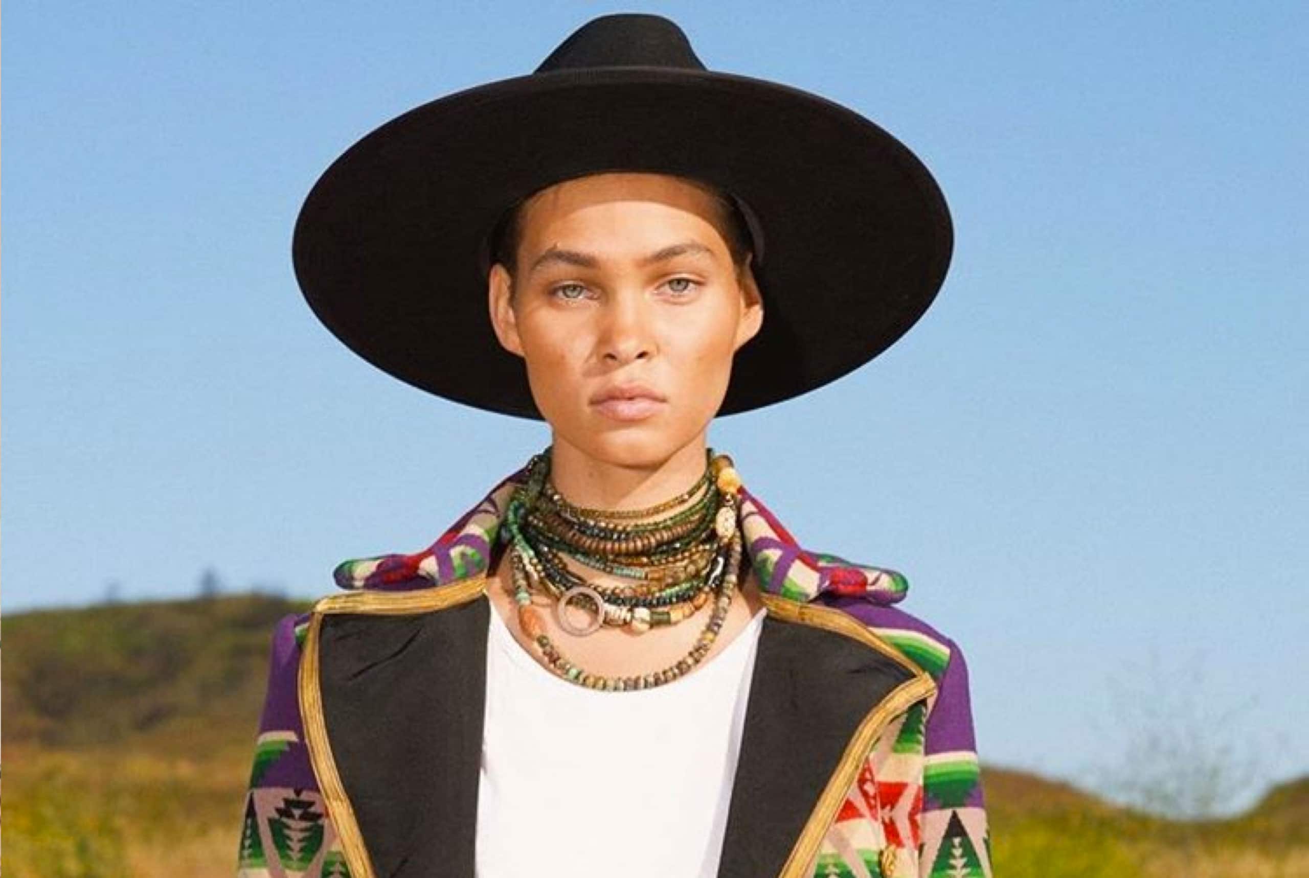 A model on a hillside wearing a wide-brim hat and a patterned Greg Lauren jacket